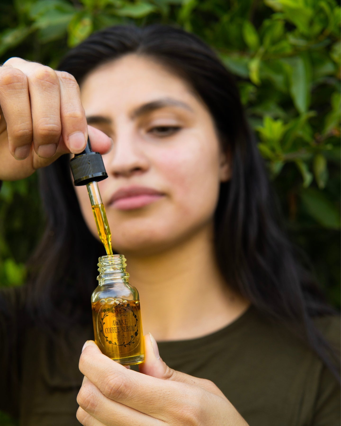 A close-up shot of a woman removing the dropper from the Awake Coffee Serum.