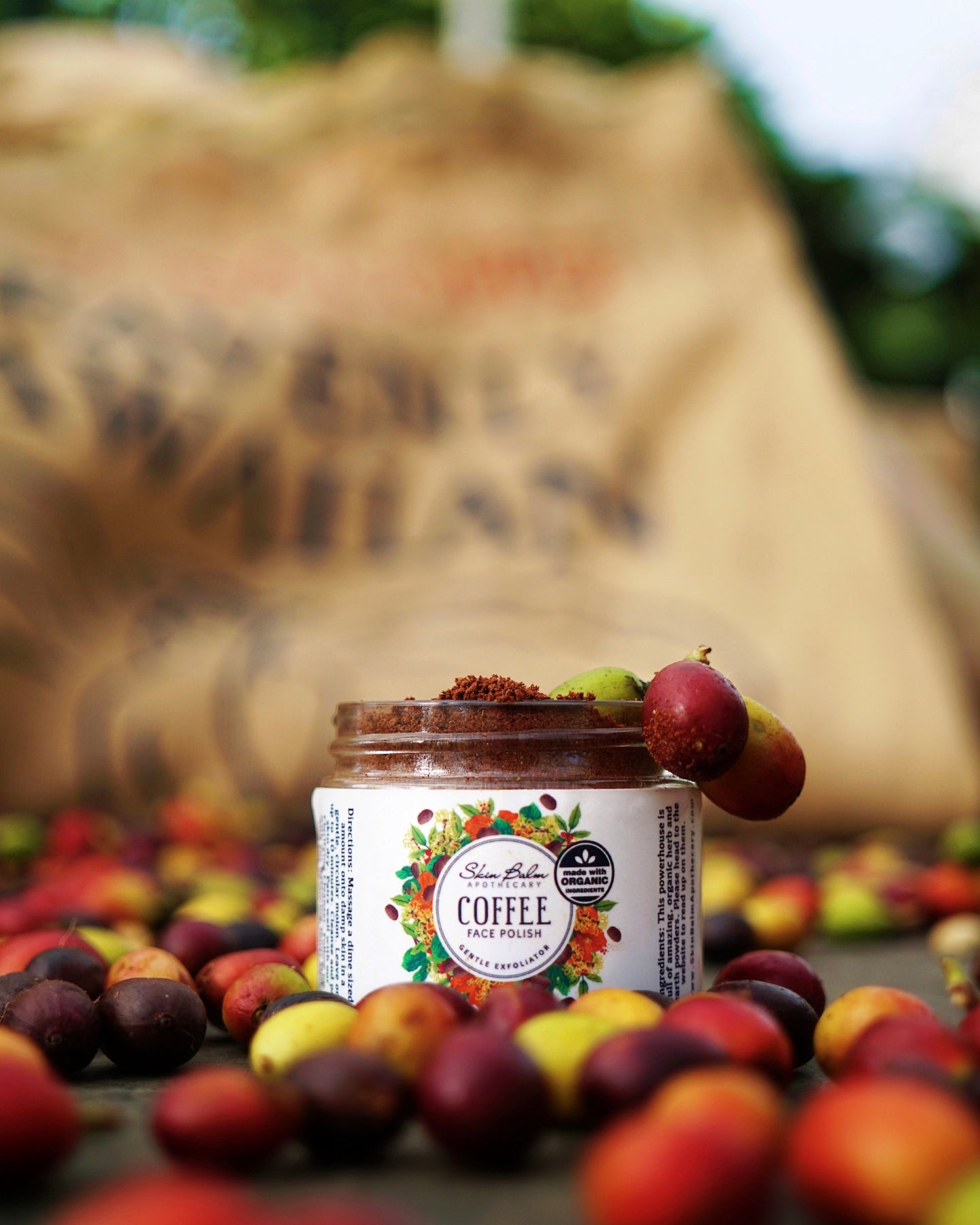 Coffee Face Polish surrounded by coffee cherries with a burlap sack blurred in the background.